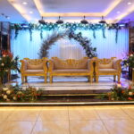 Elegant wedding stage with golden ornate sofas, floral decorations, and soft ambient lighting.